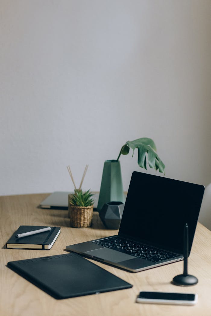 A minimalist home office setup featuring a laptop, notebook, and plant for a productive workspace.